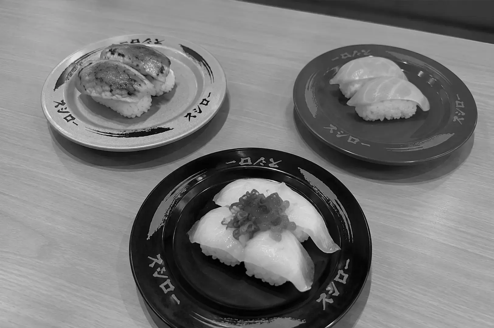 Assorted sushi plates featuring grilled eel, white fish, and topped nigiri on a wooden table.