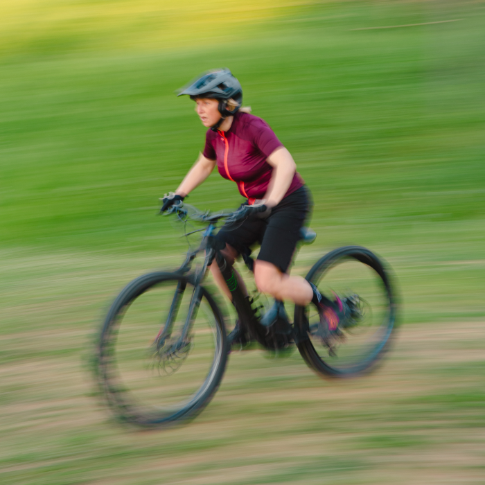 A mountain biker wearing protective gear while riding a mountain bike on a single track trail