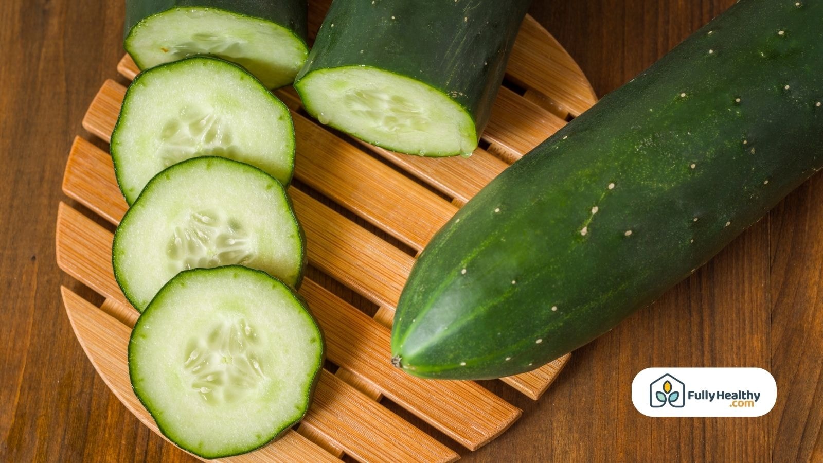 Fresh cucumbers sliced on wooden board with whole cucumber beside
