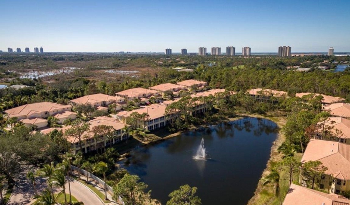 The image showcases a luxurious resort-style pool area, complete with a heated swimming pool, a relaxing spa, and comfortable outdoor seating surrounded by lush greenery. This inviting space embodies the ultimate Florida lifestyle, perfect for enjoying peaceful mornings in the Coconut Shores community.