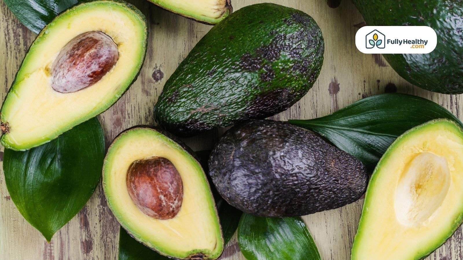 Fresh whole and halved avocados with green leaves