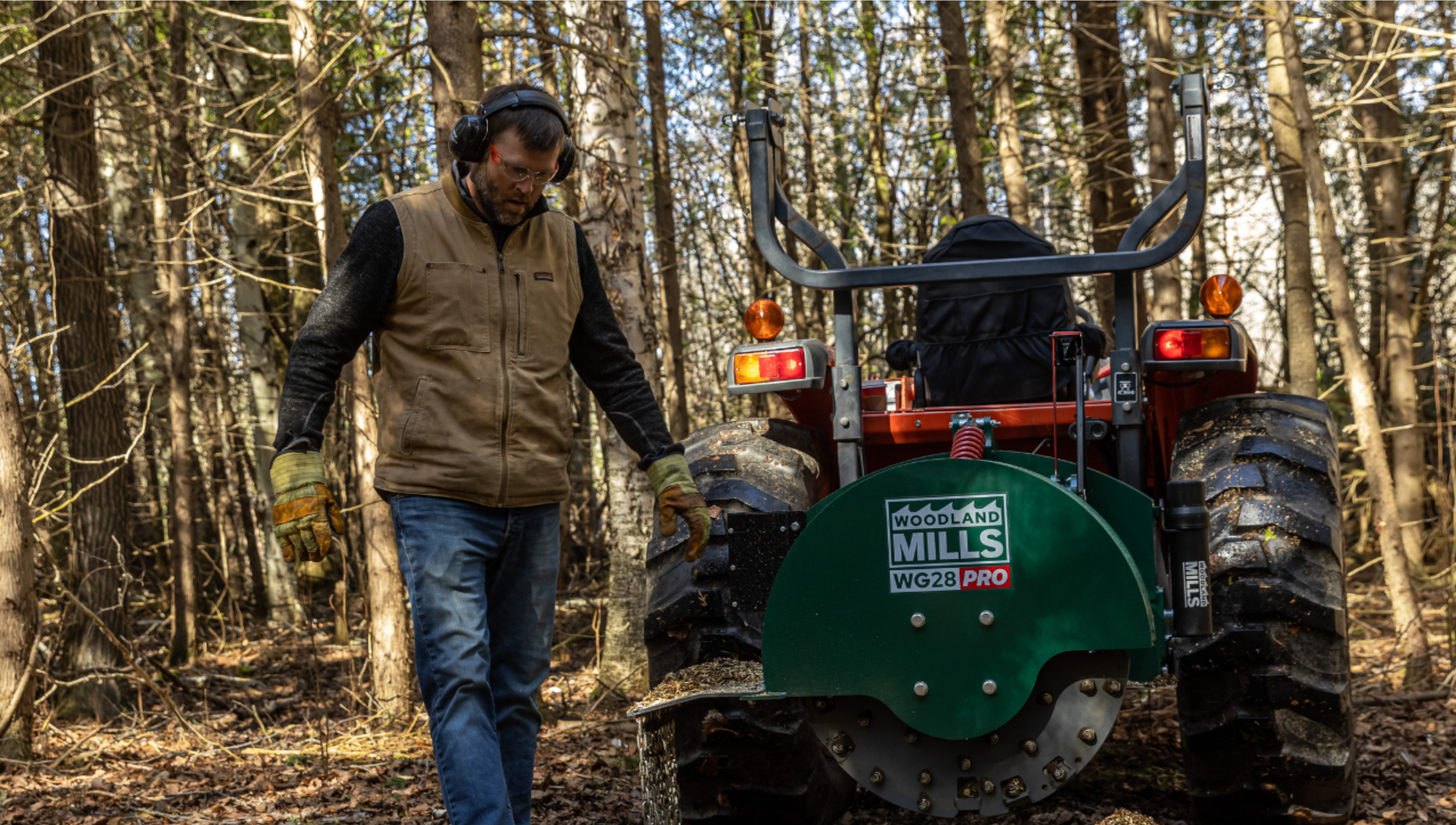 A landowner walking around his Woodland Mills WG28 PRO Stump Grinder in a forested area. 