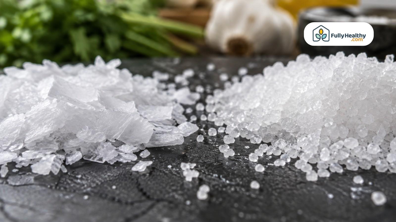 Close-up comparison of flaky kosher salt and coarse sea salt crystals on stone