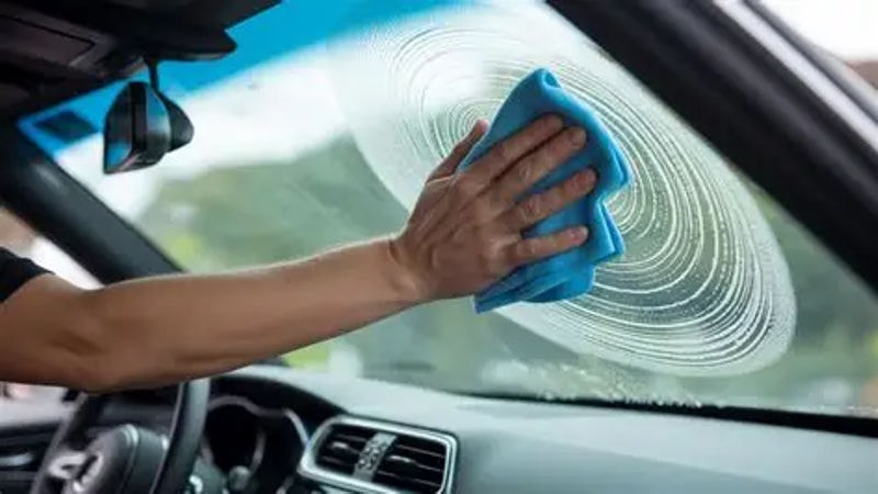 wipe the windshield in circular motion using blue cloth