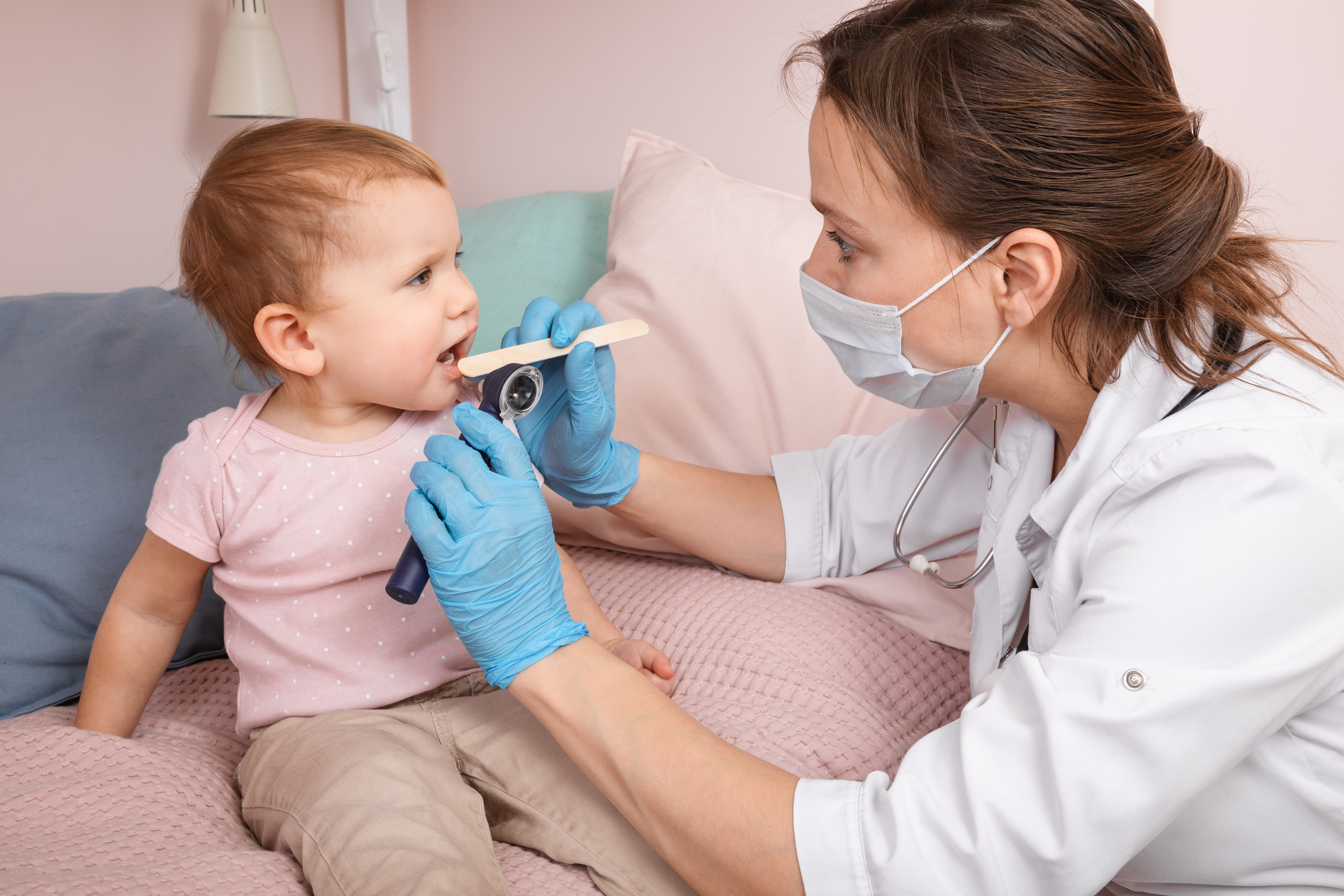 An image of a doctor checking a toddler's throat for strep throat. 