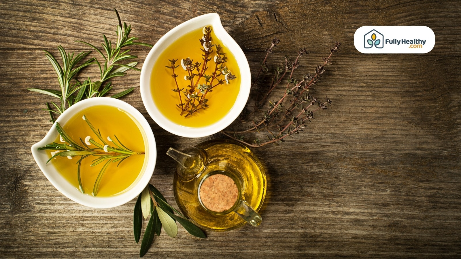 Olive oil in bowls with herbs and leaves on wooden table