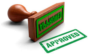 A wooden rubber stamp with the word "APPROVED" stamped in green ink.