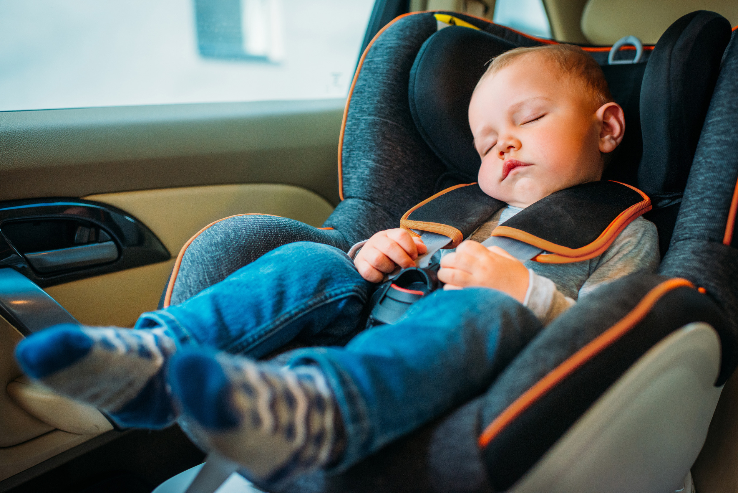 An image showing a child properly secured in a car seat, in accordance with Michigan car seat laws as recommended by the American Academy of Pediatrics.