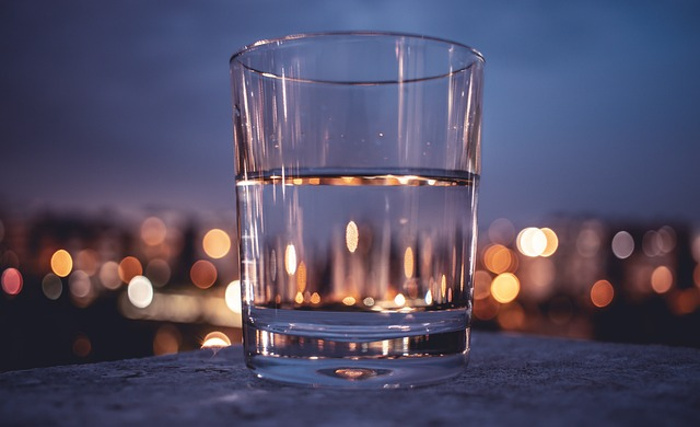 An image of a glass of water with a blurred lights in the background. 