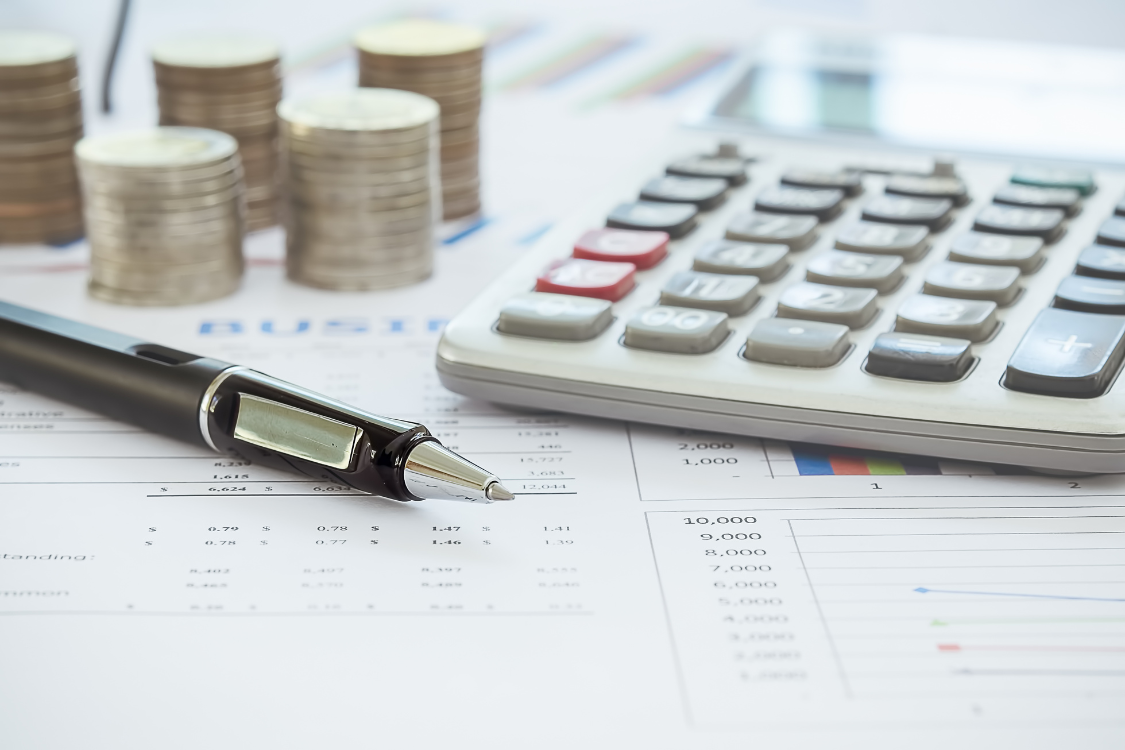 Stacked coins and calculator on financial documents representing payroll management and Social Security System (SSS) contributions in the Philippines