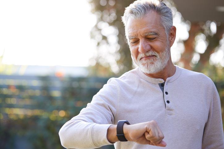 Older man with gray hair checking his smart watch. 