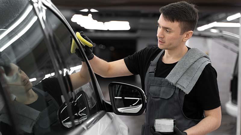 A man applying wax to his car