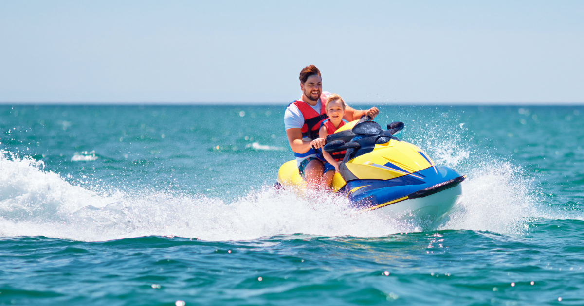 Father and child riding a jet ski on the bay, enjoying water activities near a New Jersey Shore bayfront rental.