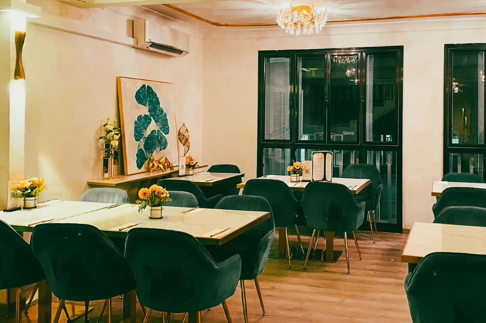 Eye-level shot of an elegant halal restaurant interior with marble-top tables, upholstered seating, warm chandelier lighting, and a refined cozy dining atmosphere.