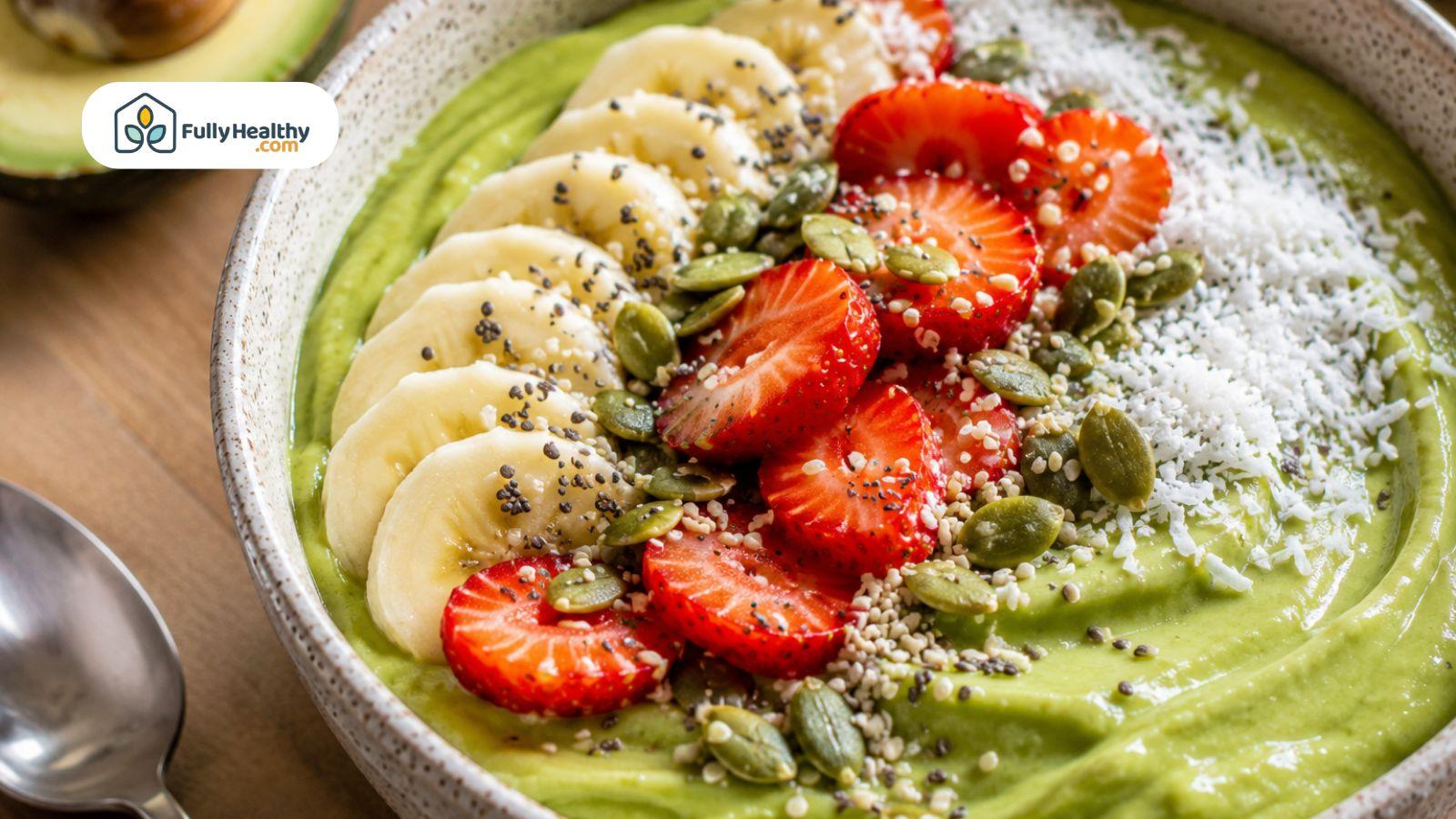 Avocado smoothie bowl topped with bananas strawberries coconut seeds and healthy breakfast ingredients.