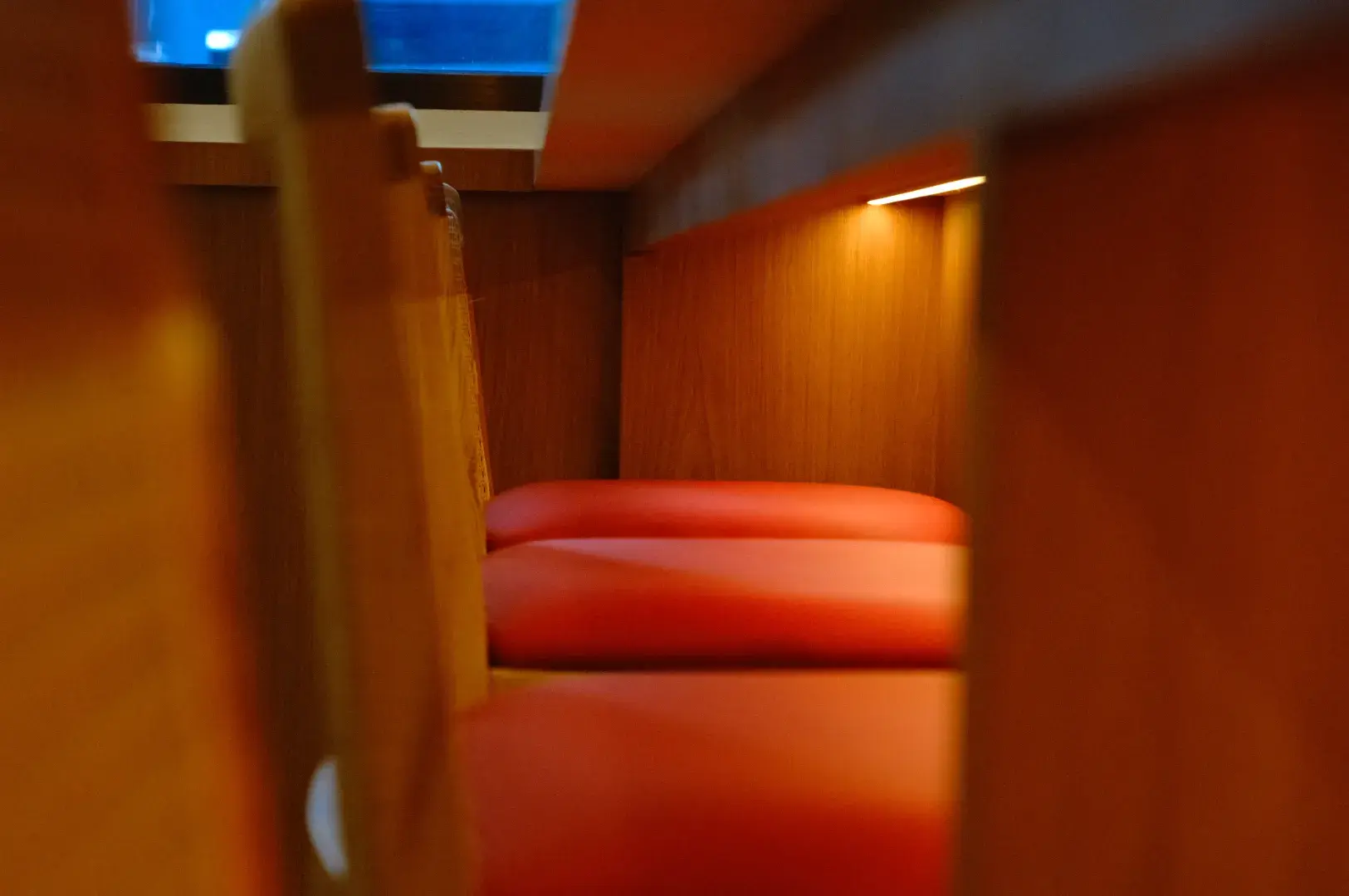 A close-up view of a wooden seating area with red cushions, showing the structure and design of the space.