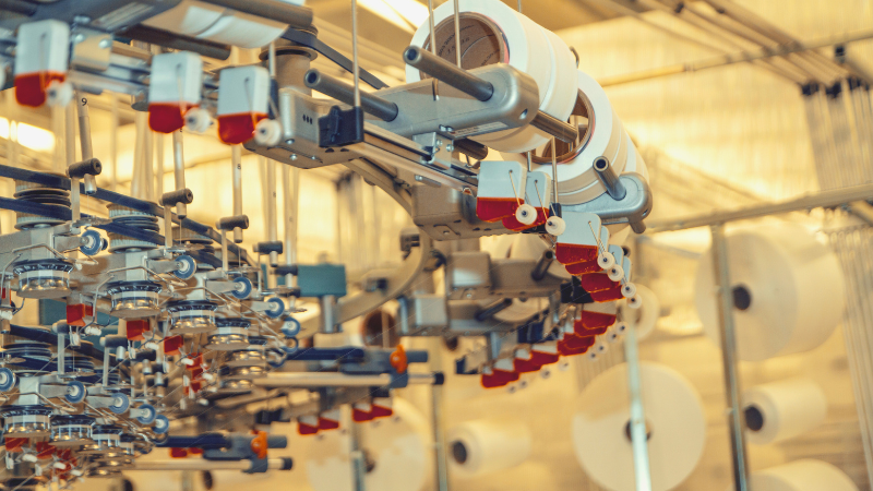 Open-loop systems featuring industrial machinery with spools of white thread, some accented in red, against large white rolls of material.