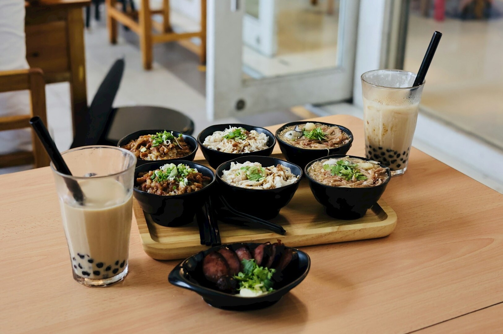 A table displaying an assortment of food bowls and drinks, featuring milk tea among the items.