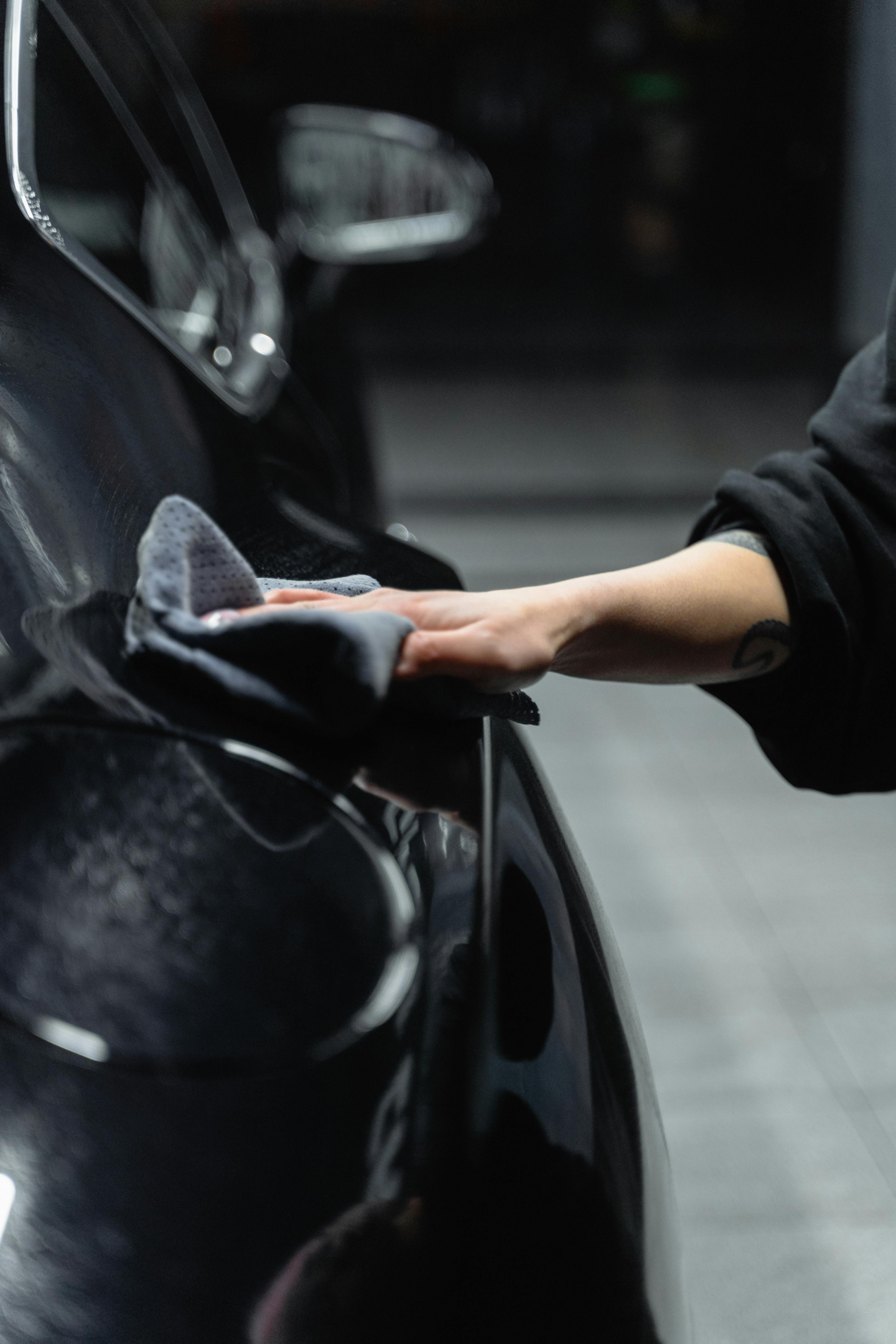 Hand Shown Wiping Side of Black Luxury Car With Microfiber Rag