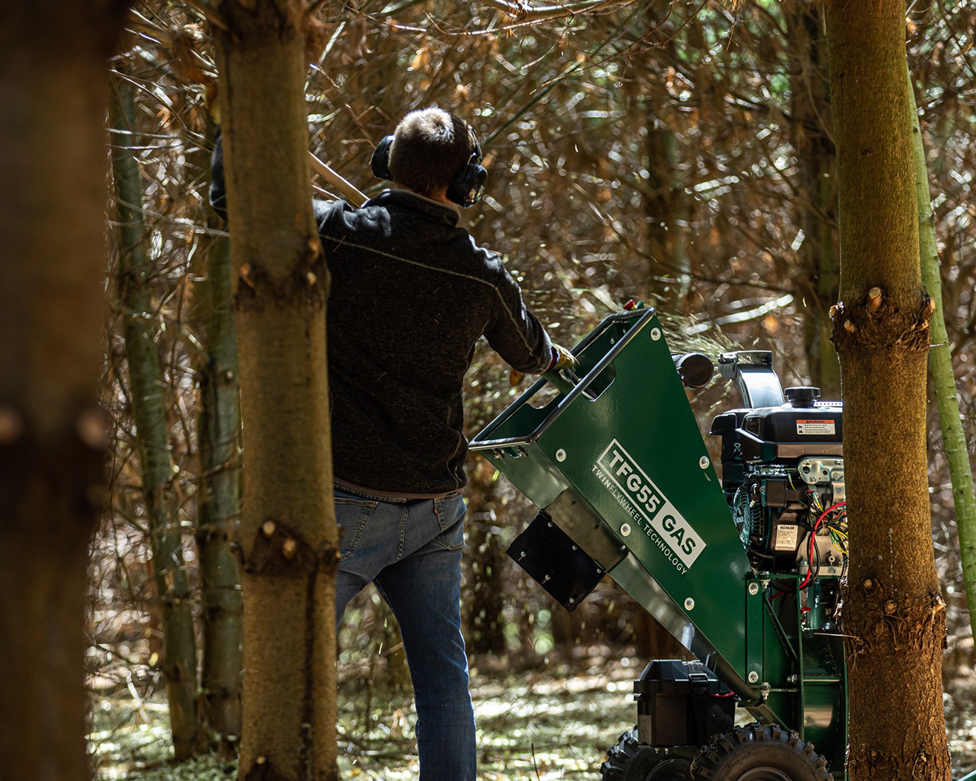 A man uses a Woodland Mills TF55 GAS Wood Chipper in the woods.