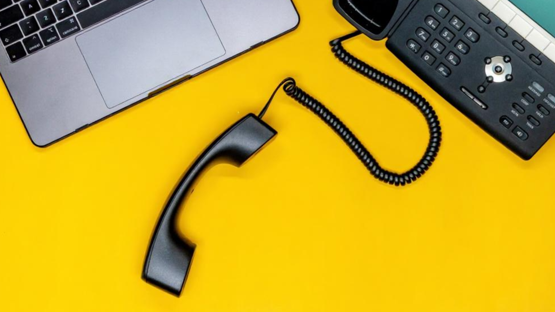 Laptop and VoIP phone on yellow background with detached handset, referencing phone number porting and compatibility with existing hardware.