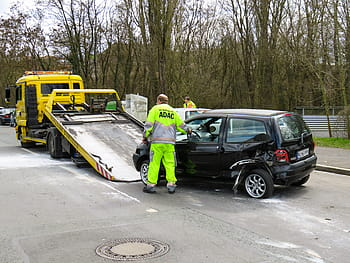 A tow truck removing a junk car from a driveway