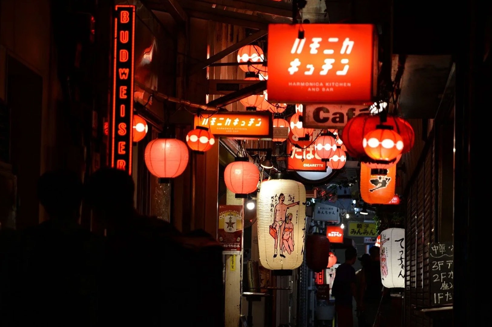 Japanese izakaya alley with glowing lanterns and restaurant signs at night.