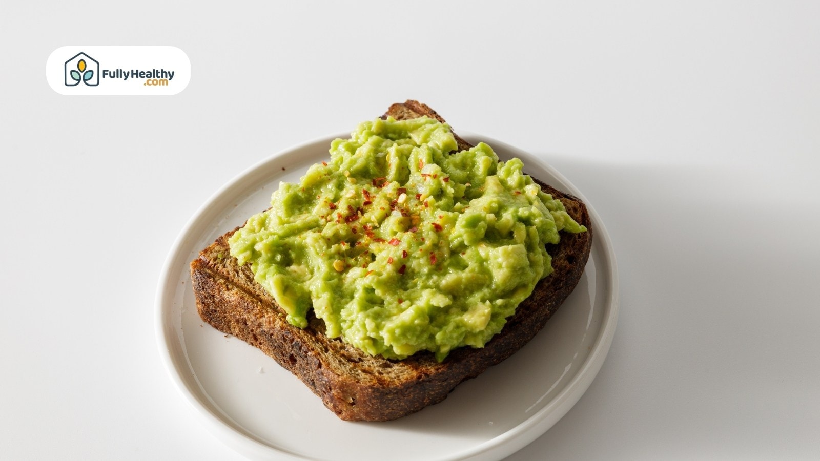Toasted bread slice topped with mashed avocado and sprinkled red pepper