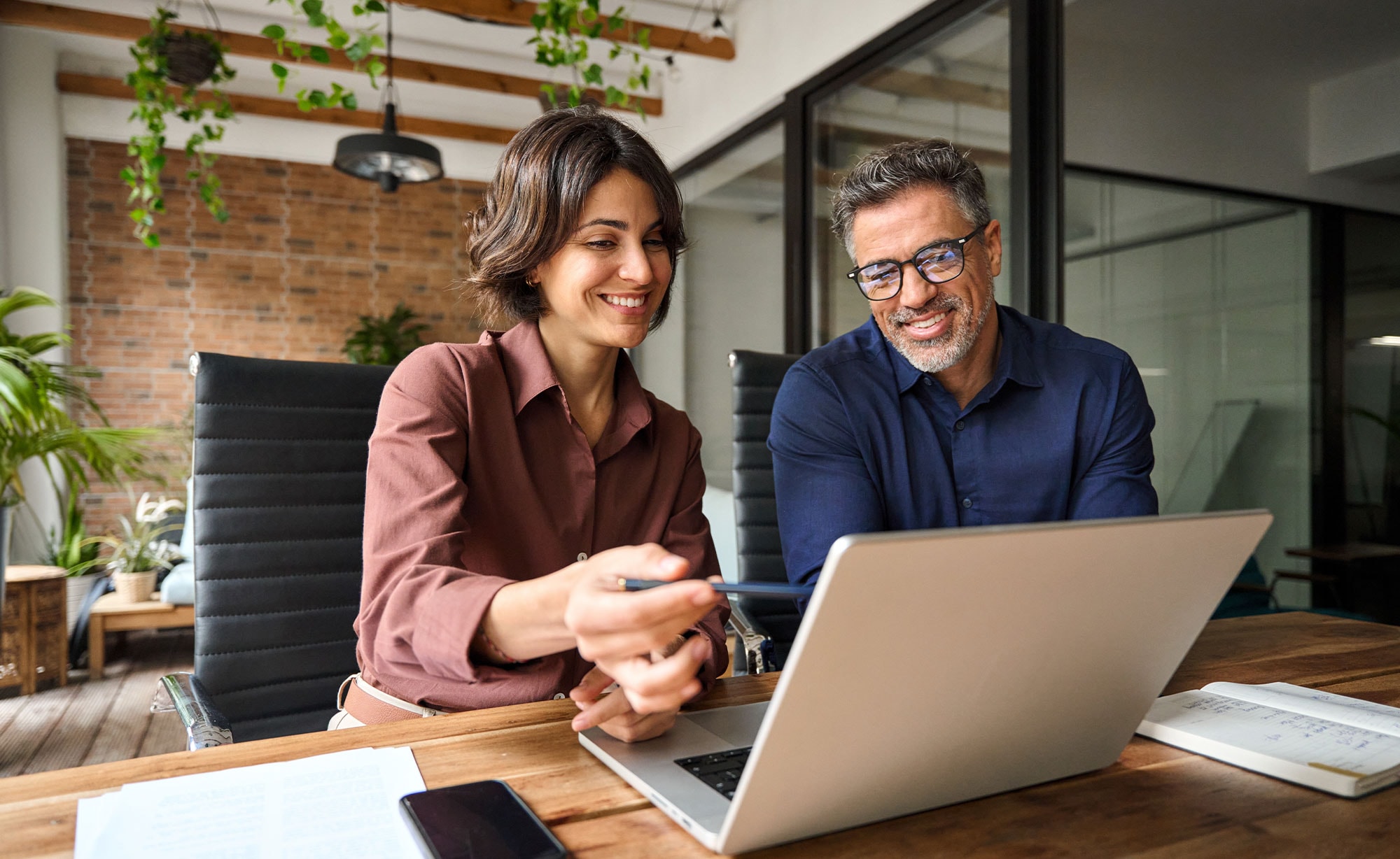 Two insurance professionals reviewing policy data on a laptop, showcasing the usability of modern agency management systems.
