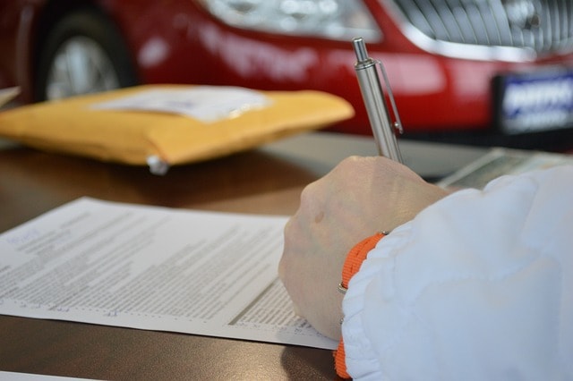 Military spouse signing paperwork to seek debt relief through student loan forgiveness programs.