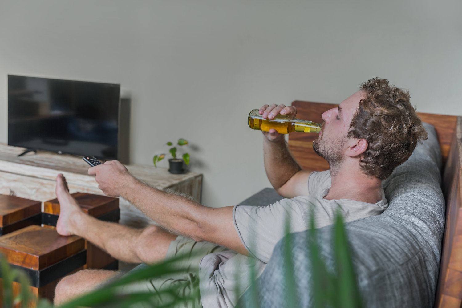 Man drinking while getting comfy at home.