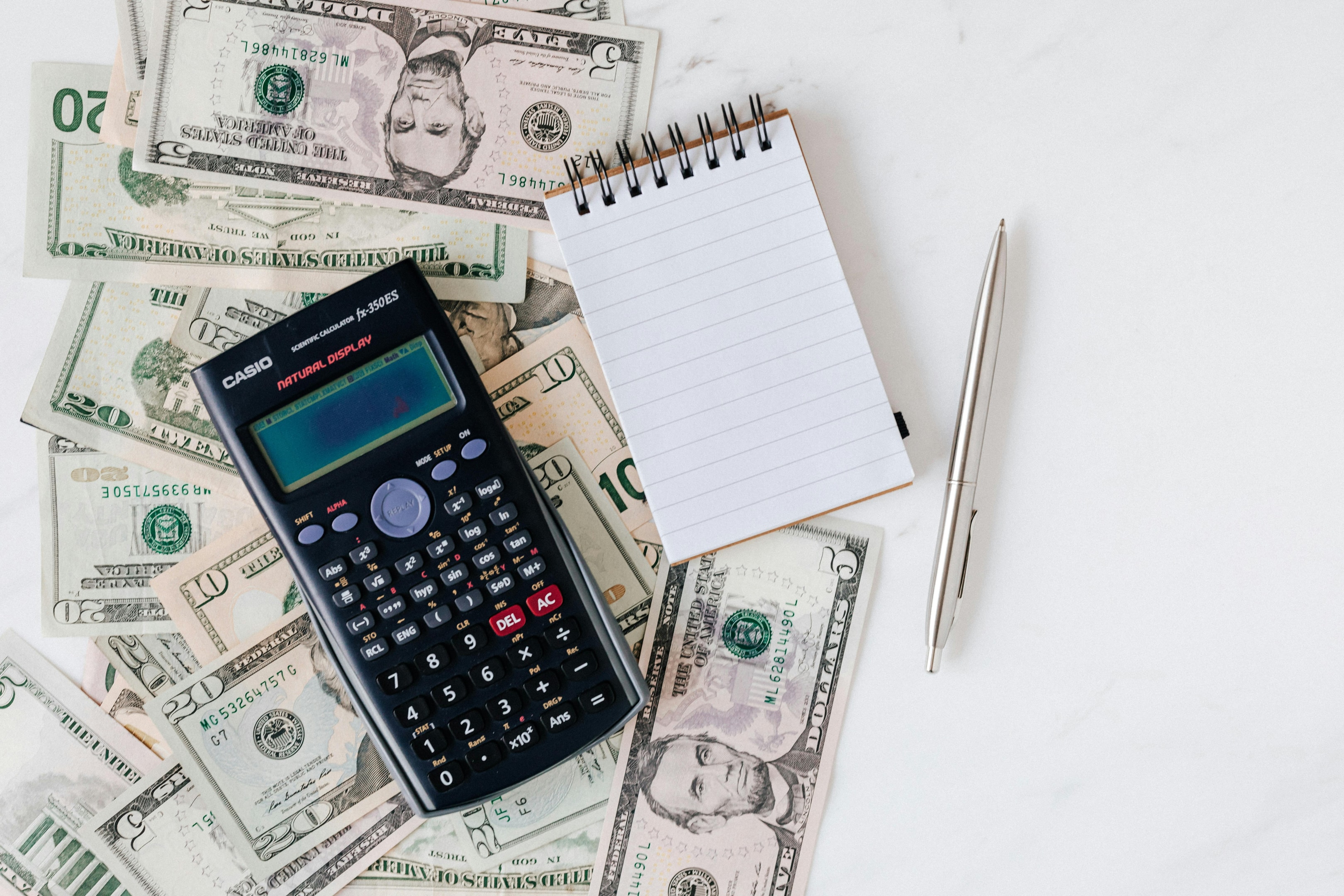 Cash laid out with calculator and notebook for calculating rental income. 