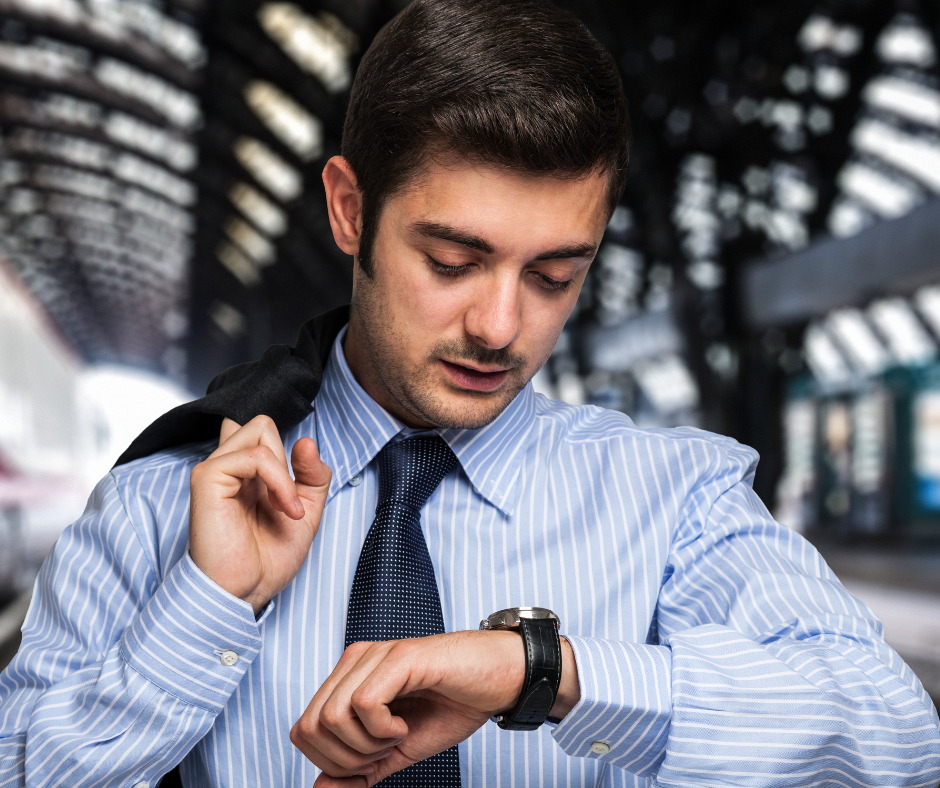 A commuter checking their watch while waiting for a train, highlighting time management for daily commuters.