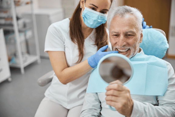 senior male admires his new permanent replacement tooth