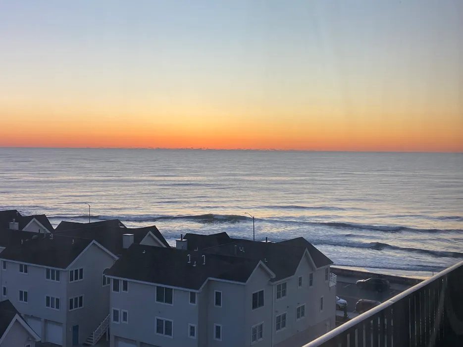 Sunrise ocean view from Regency Towers in North Wildwood, NJ, overlooking rooftops and the beach with waves gently rolling in.