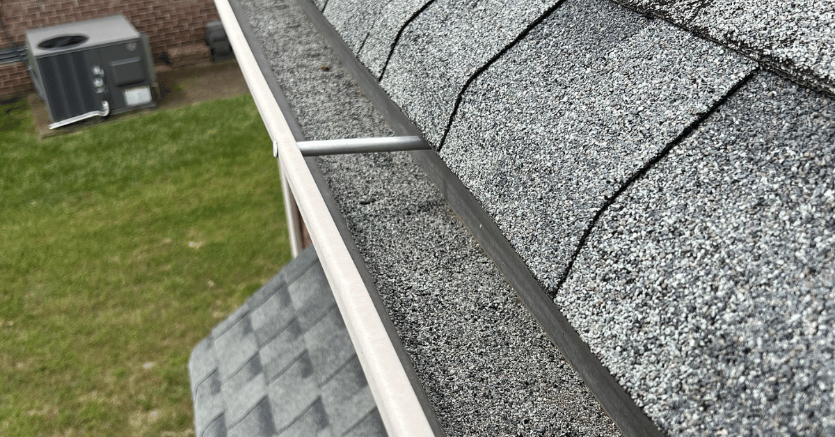 Close-up of gutter packed with granules from asphalt shingles, a common sign of heat damage and UV deterioration.