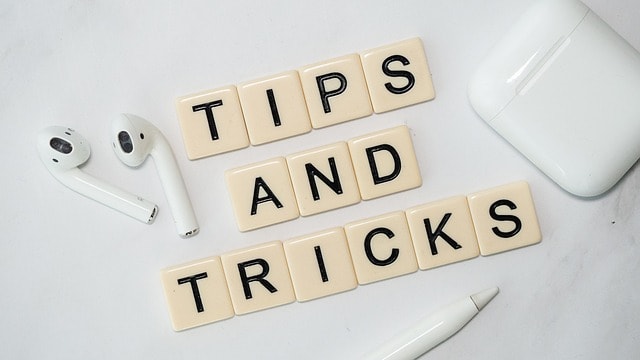 Tips and tricks spelled with Scrabble letters, Airpods, and a pen