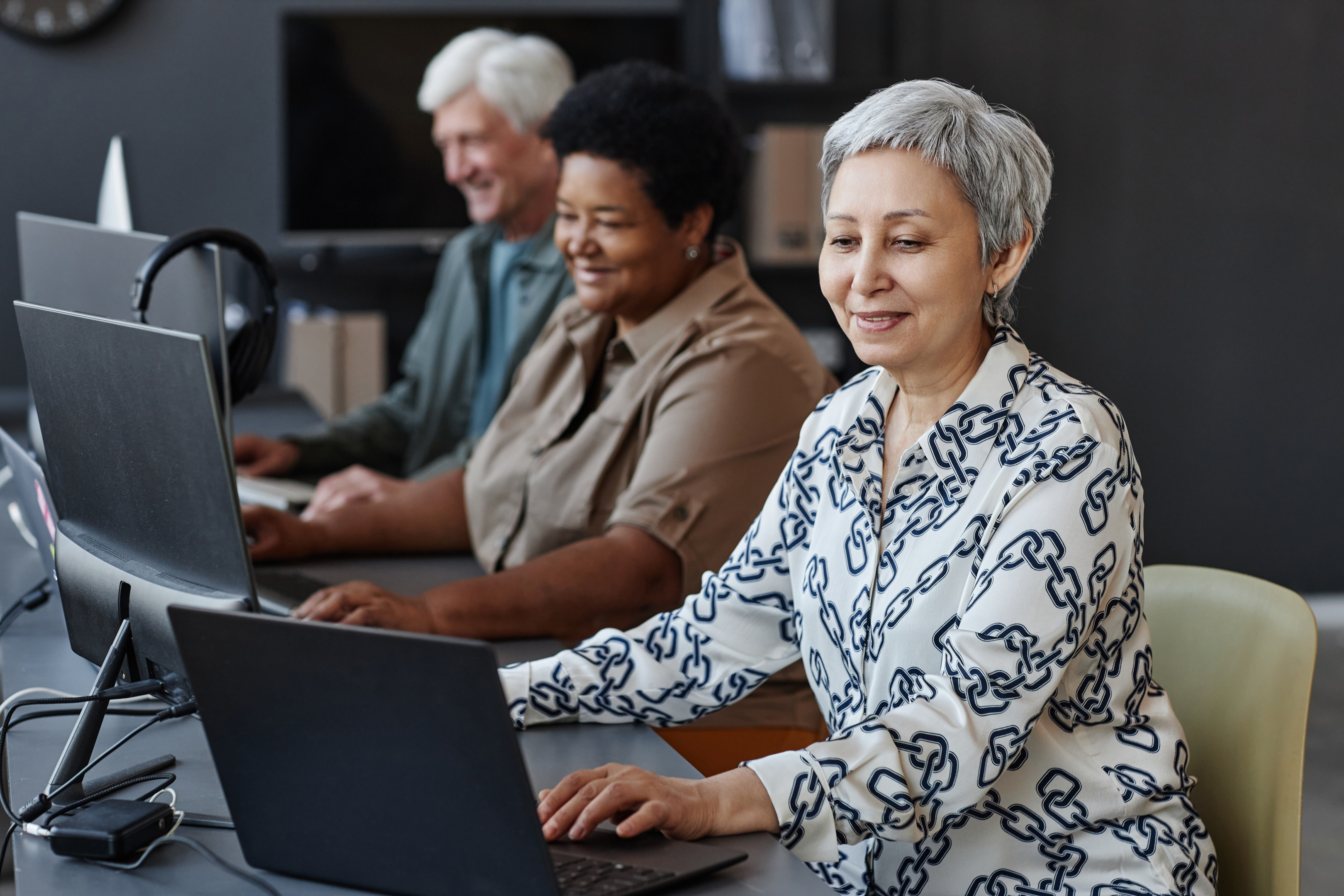 "A senior Asian woman confidently navigating a programming class – a vivid testament against age discrimination in the learning and working environments."