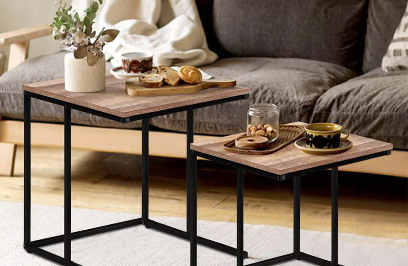 A set of Artiss industrial/rustic style nesting tables, holding a vase of flowers, two cups of coffee and a variety of nuts and pastries.