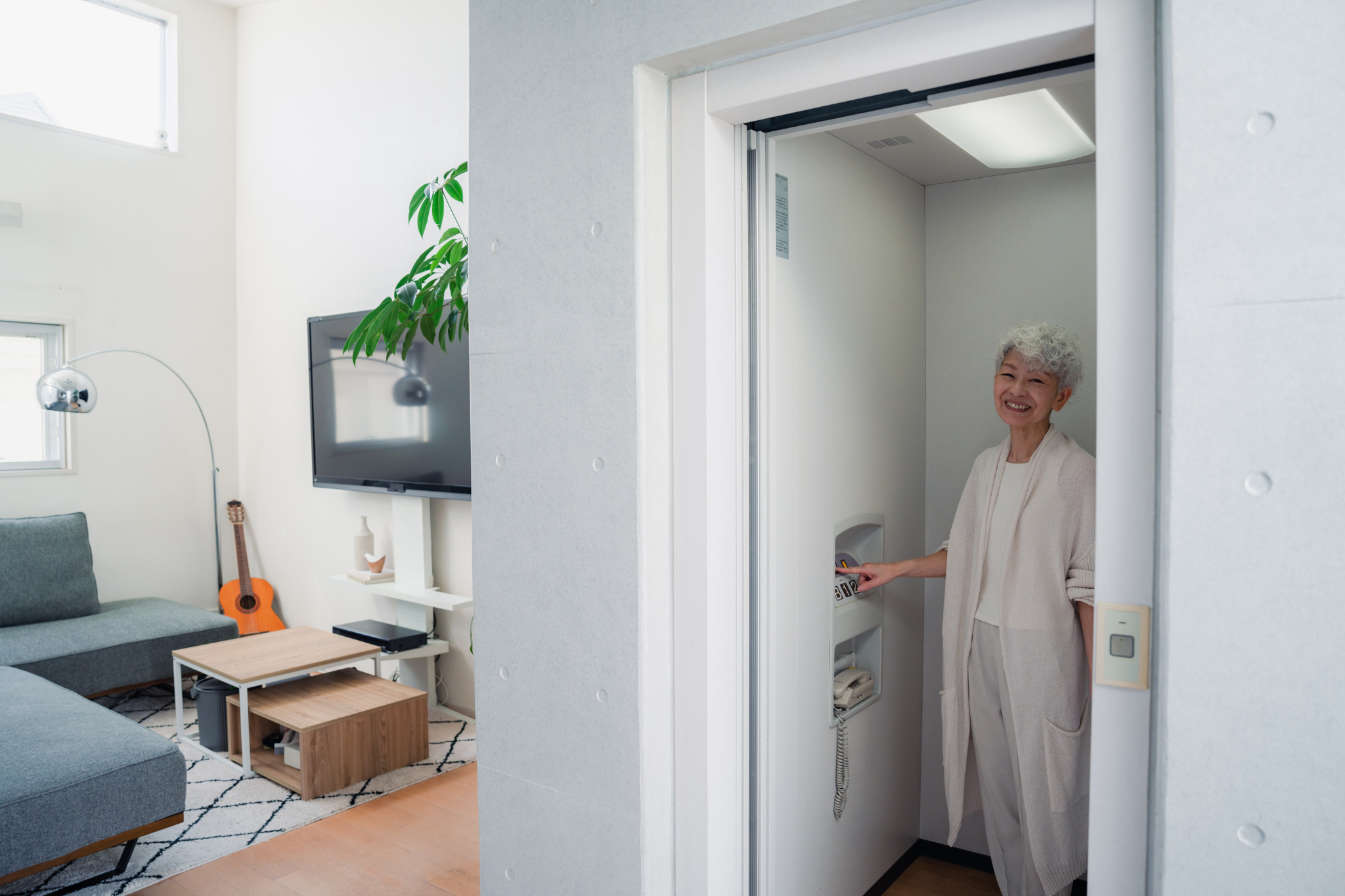 An elderly women standing inside a platform lift in her home.