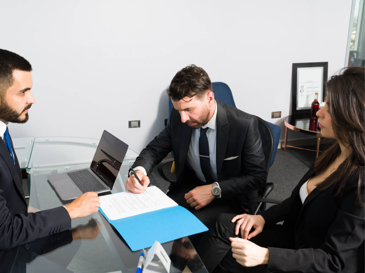 A professional looking couple consulting with a lawyer and signing documents