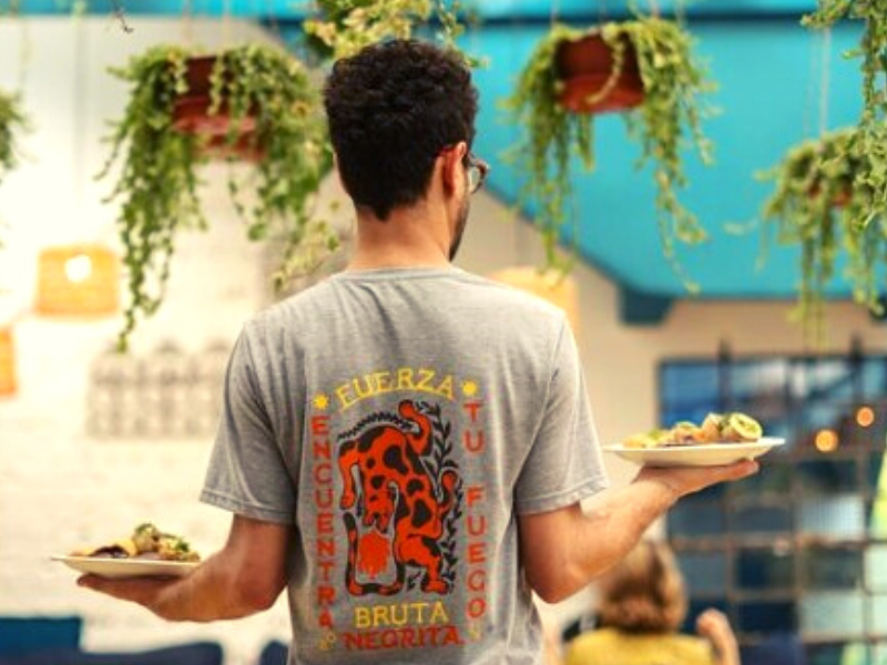 Homem serve pratos no Botanique Café em Curitiba - PR.