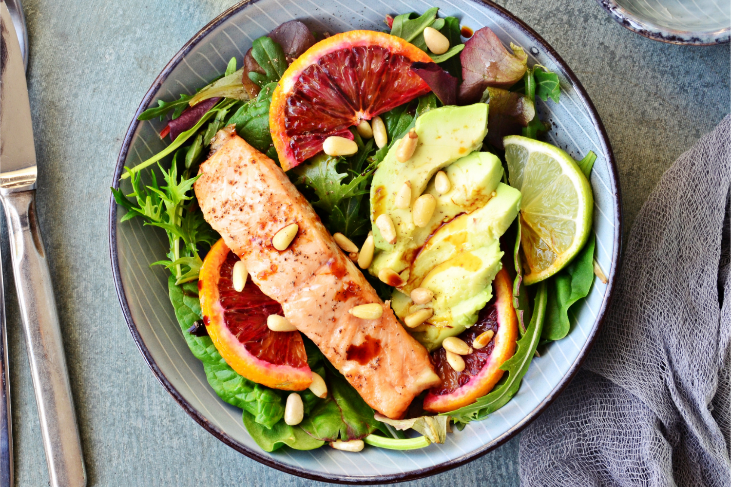 A plate of healthy food with avocado, salmon, and leafy greens.