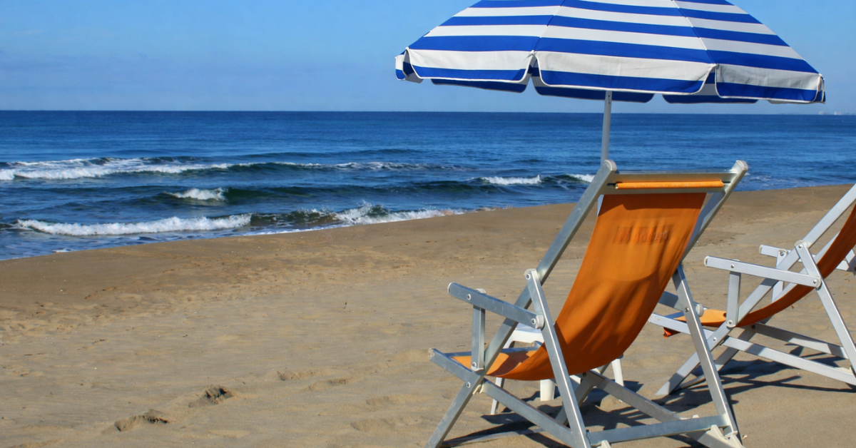 Oceanfront beach chairs with blue and white striped umbrella overlooking the New Jersey Shore coastline
