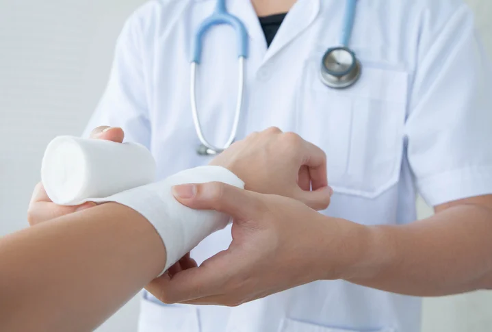 A doctor covering an arm with bandage