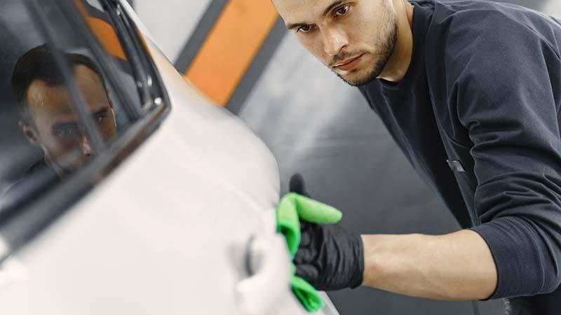 A man polishing his car with a microfiber cloth