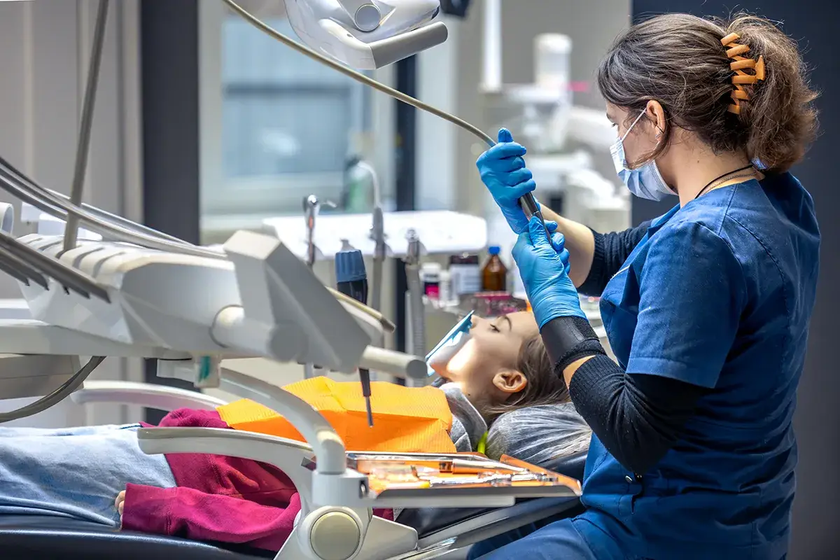 Dental professional treats patient in modern clinical treatment room setting.