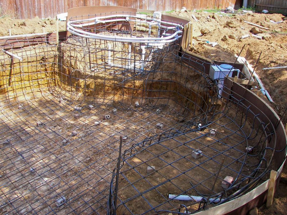 Steel rebar framework and plumbing installation during the early stages of custom pool construction, illustrating how long does it take to build a pool