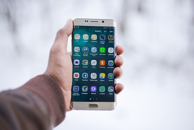 Hand holding Samsung phone with icons on display