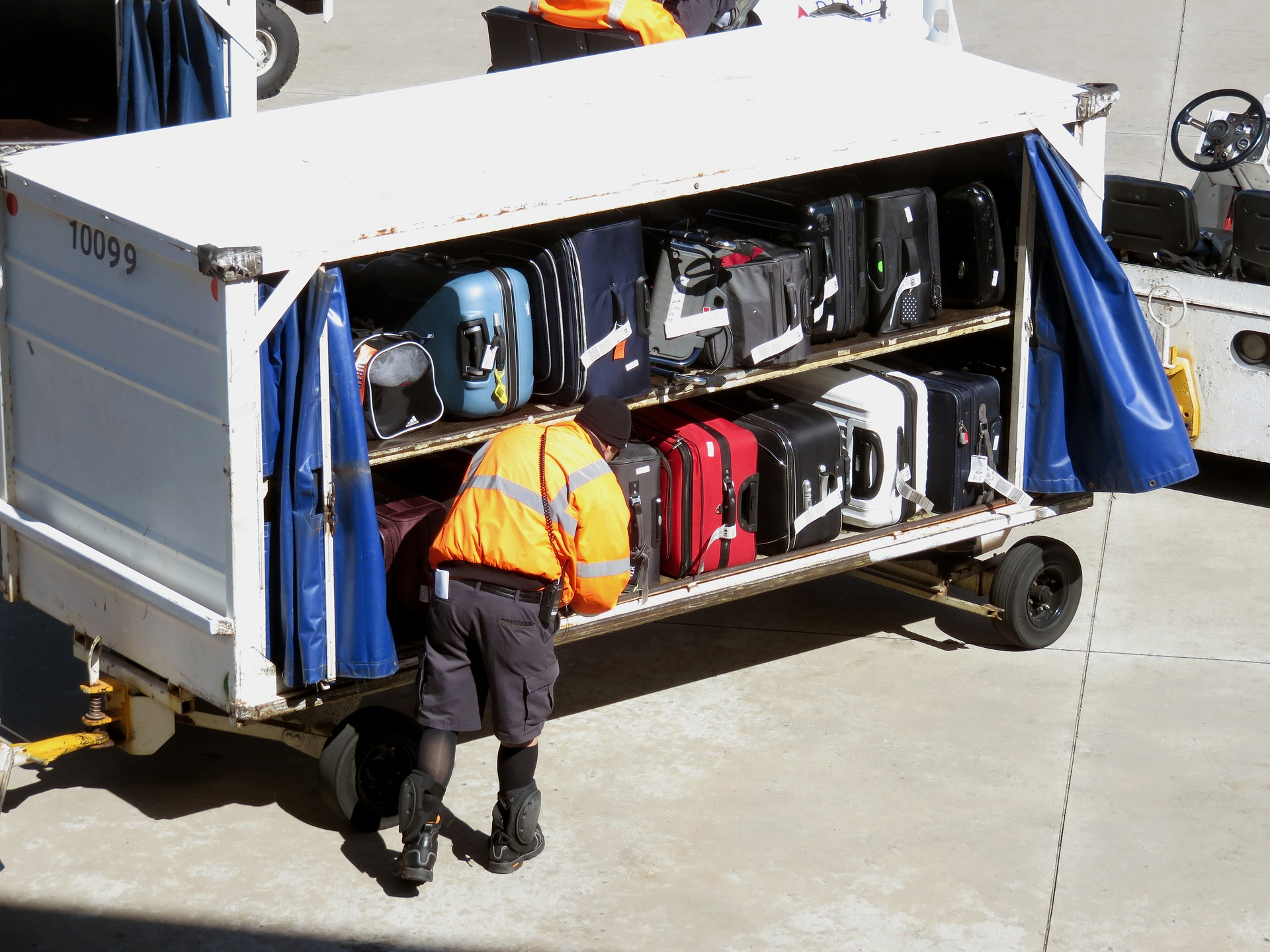 An airport worker arranging luggage to be loaded on an aircraft.
